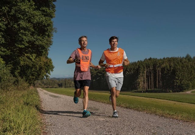 Le joggeur malvoyant Hans-Peter avec un guide pour personnes en situation de handicap visuel.
