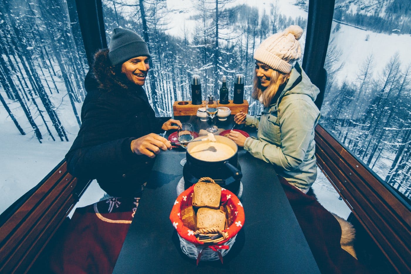 Ein Fondue hoch über Saas-Fee. Bei einer abendlichen Gondelfahrt geniessen Besuchende die einzigartige Stimmung der Saaser Bergwelt.