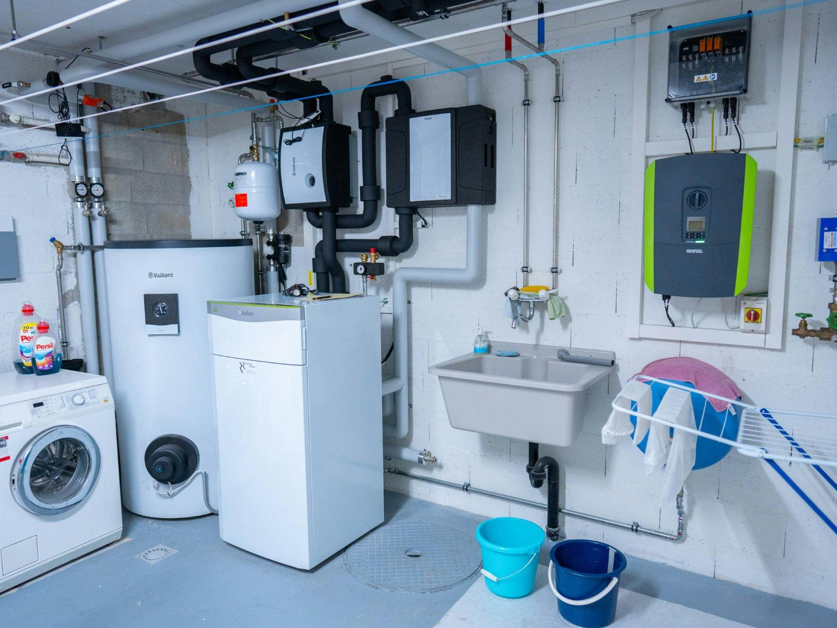 Installation der Erdwärmepumpe mit vertikalen Sonden, einem Zähler und dem Wassererwärmer in der Waschküche.