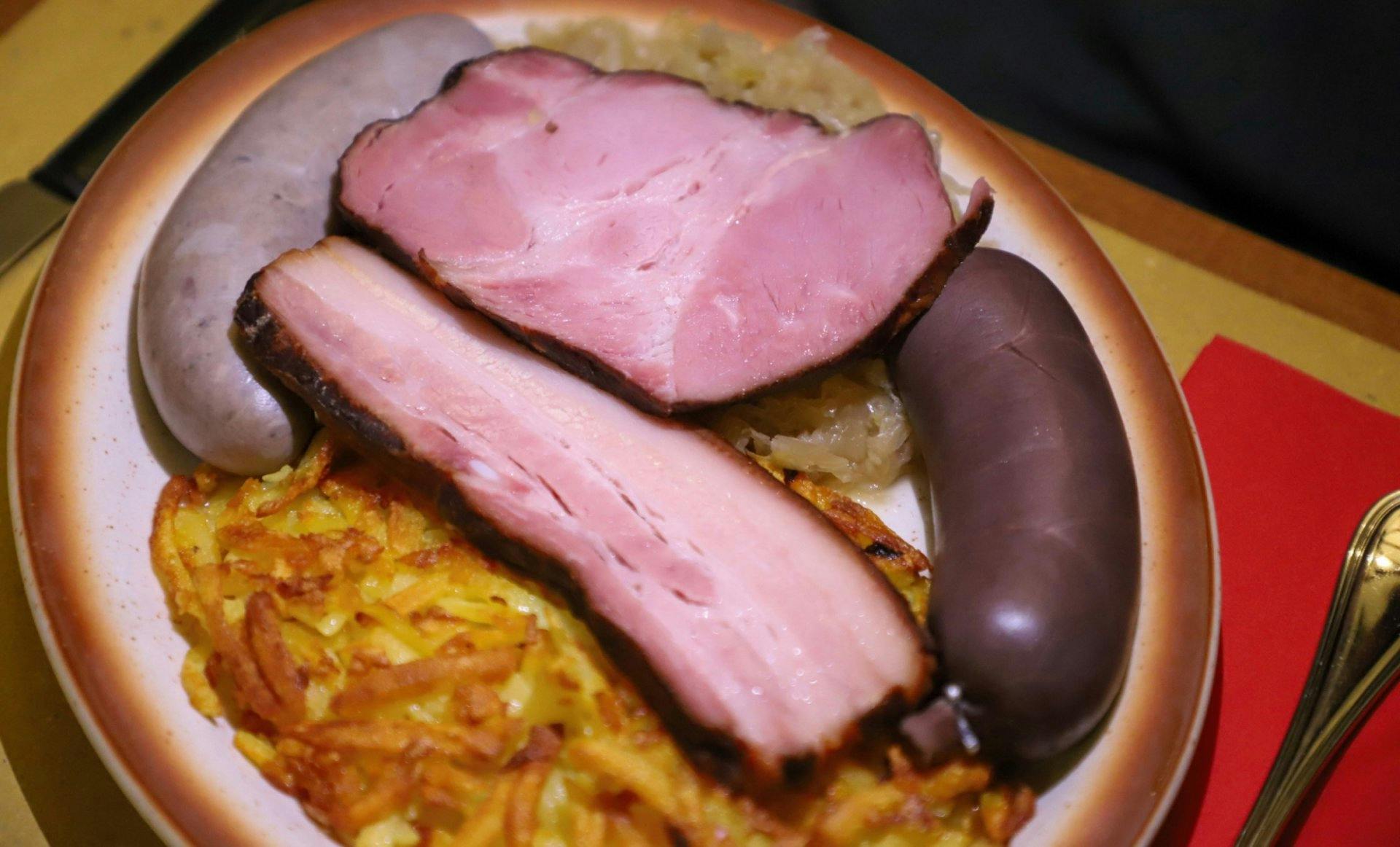 Dans l’assiette: boudin, saucisse au foie, côtes fumées et lard, accompagnés de rösti et de choucroute. Un festin servi ainsi depuis des générations.