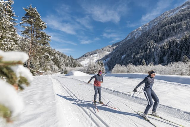 Être sportif et profiter en même temps d’un paysage hivernal de carte postale: un fondeur seul sur une piste.