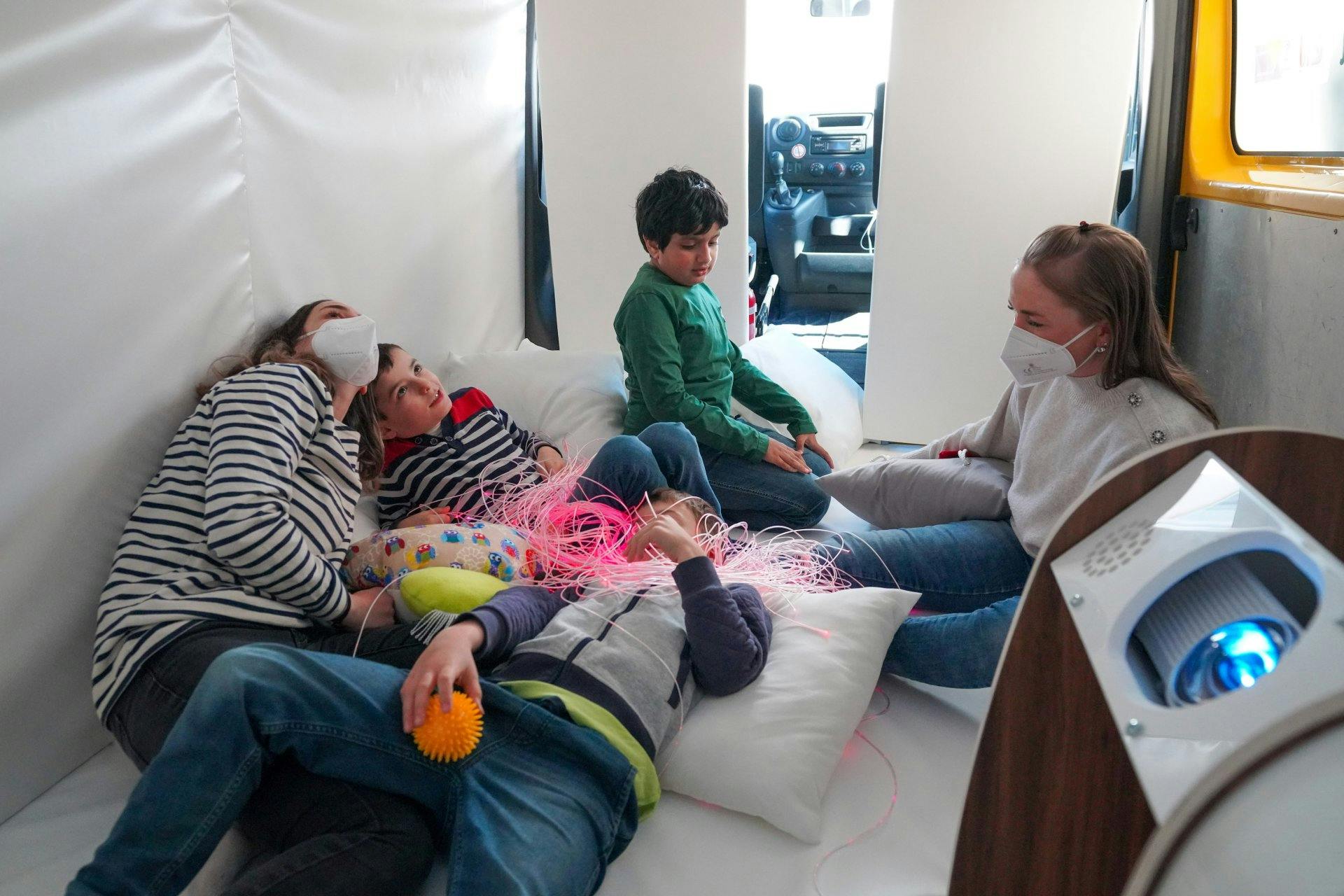 Facce felici: i bambini si lasciano guidare verso un nuovo mondo dai suoni, dalle immagini e dai materiali del bus snoezelen.