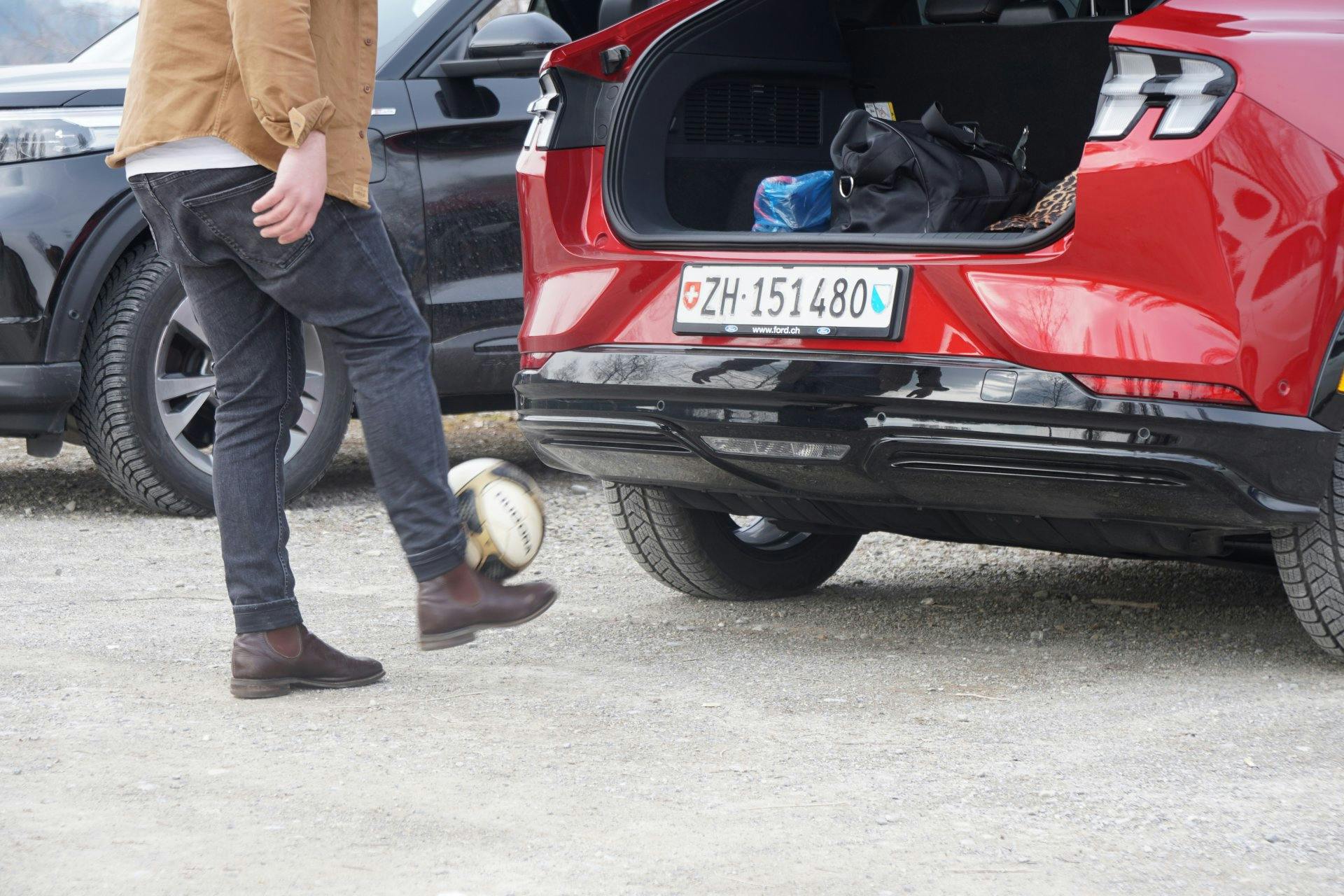 Spielpause! Fussball und Fussballschuhe hat der unbekannte Fahrer immer mit dabei. Tore schiessen mit dem neuen Ford Mustang Mach-E ist für den Hobby-...