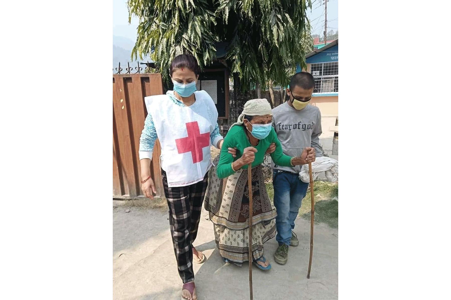 Eine ältere Person wird von Freiwilligen des Nepalesischen Roten Kreuzes unterstützt.
