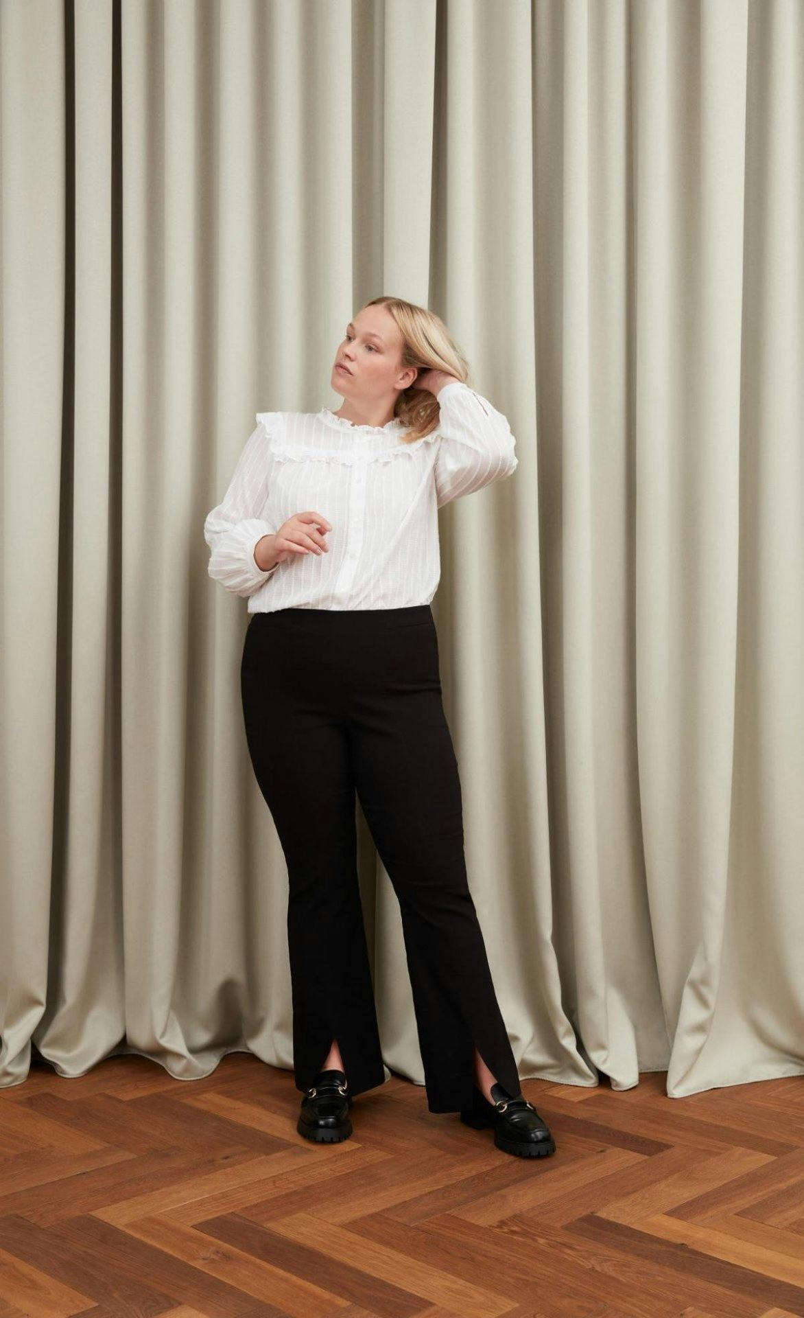 Weiss zu schwarz sieht immer edel aus – zum Hingucker wird dein Outfit mit diesem verspielten Rüschenhemd.