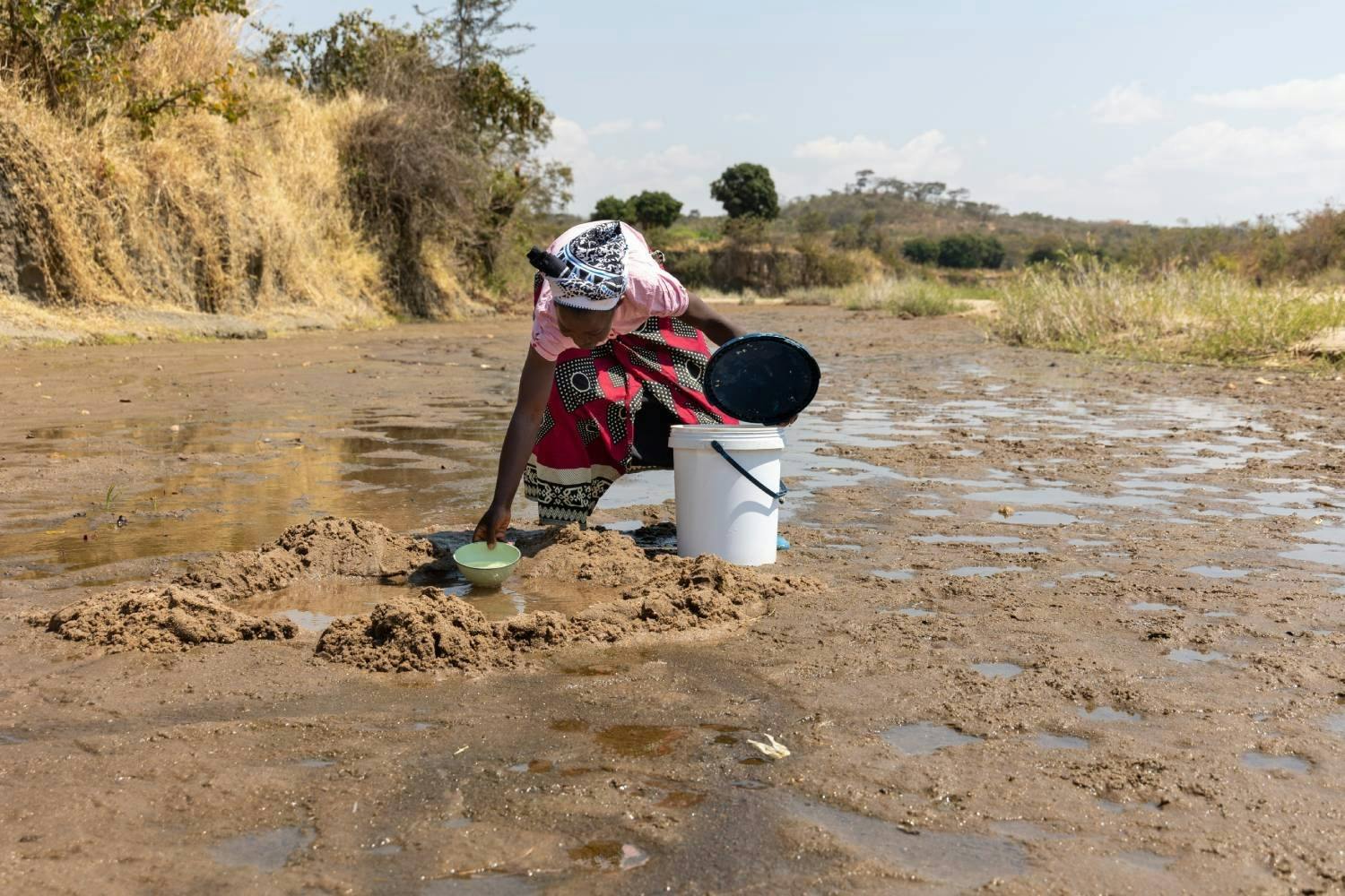 Une bénévole de la Croix-Rouge montre comment elle se procurait de l’eau auparavant. Elle creusait un trou dans la terre, attendait que l’eau s’accumu...